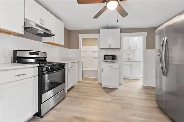 a kitchen with stainless steel appliances a refrigerator stove and white cabinets