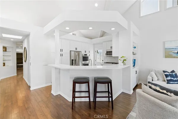 a kitchen with stainless steel appliances granite countertop a stove a sink dishwasher and a refrigerator with wooden floor