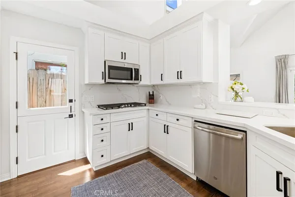 a kitchen with granite countertop white cabinets and stainless steel appliances