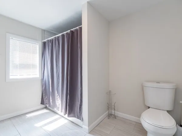 a bathroom with a toilet a window and shower