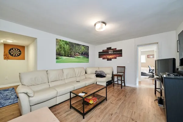 a living room with furniture a wooden floor and a flat screen tv