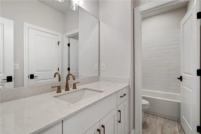 a bathroom with a granite countertop sink and a mirror with bathtub
