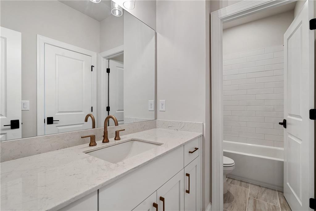 502 Whatton Road, Unit 1 Johns Creek, GA 30022 - Photo 24 of 34 a bathroom with a granite countertop sink and a mirror with bathtub