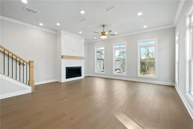 an empty room with wooden floor fireplace and windows