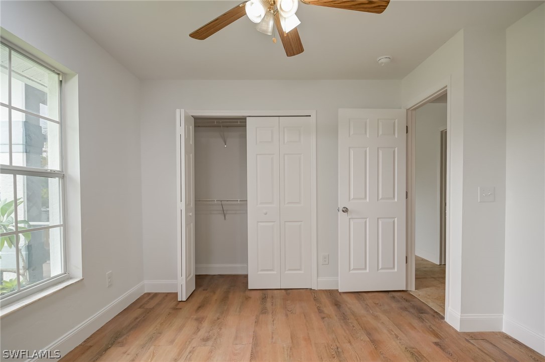 18298 Hepatica Road Fort Myers, FL 33967 - Photo 16 of 25 an empty room with wooden floor chandelier fan and windows