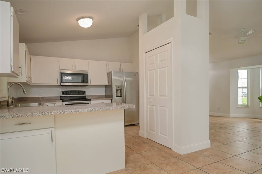 18298 Hepatica Road Fort Myers, FL 33967 - Photo 8 of 25 a kitchen with stainless steel appliances granite countertop a refrigerator a stove a sink a microwave oven with white cabinets