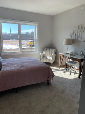 a bedroom with a bed a dresser and next to a window
