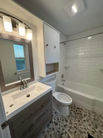 a bathroom with a bathtub shower sink mirror and toilet