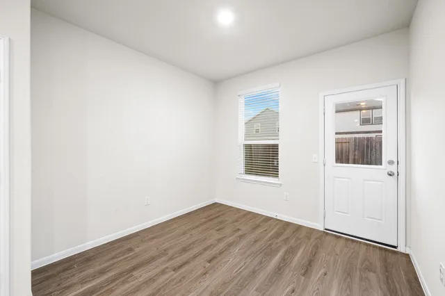 an empty room with wooden floor and windows