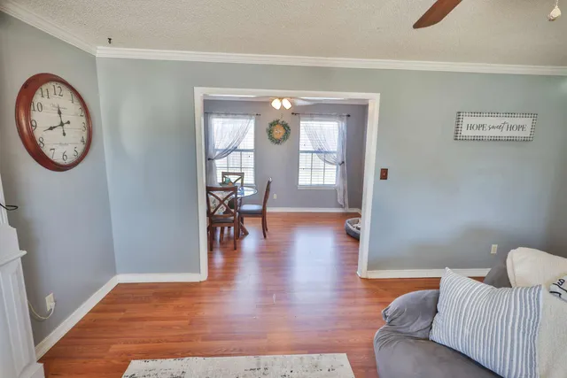a view of a livingroom with furniture a fireplace mirror and wooden floor