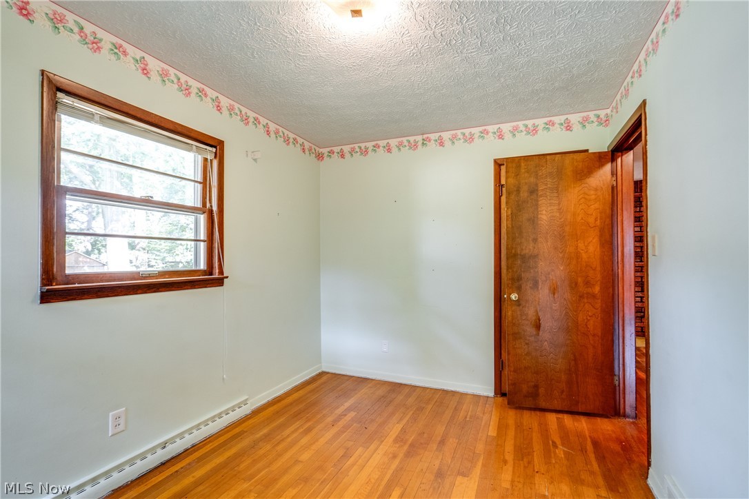3799 Boydell Road Kent, OH 44240 - Photo 16 of 21 Unfurnished room featuring a textured ceiling, a baseboard radiator, and wood-type flooring