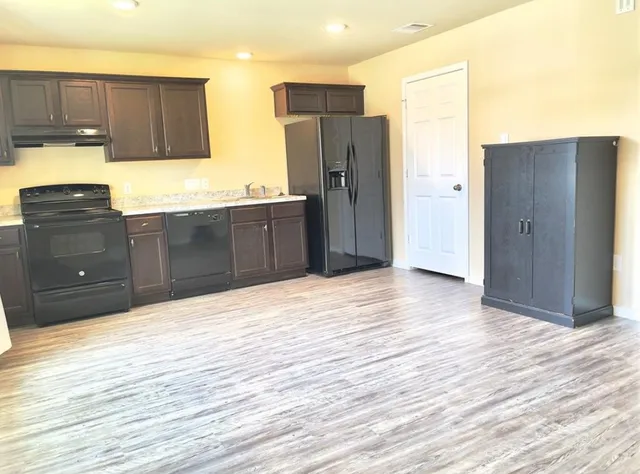 a kitchen with granite countertop wooden cabinets and refrigerator