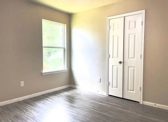 an empty room with wooden floor and a window