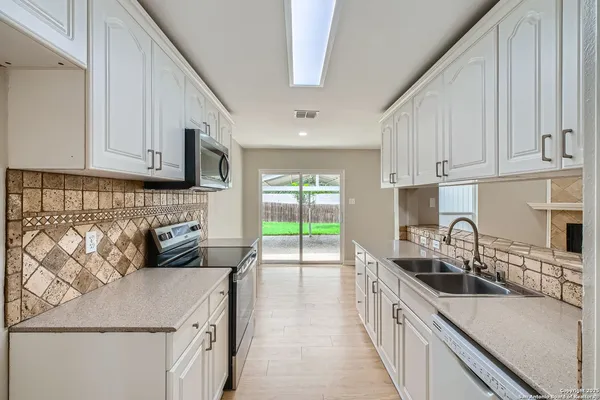 a kitchen with kitchen island granite countertop a sink and a stove top oven