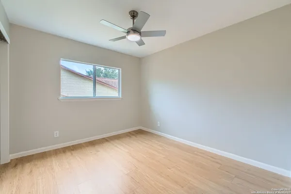 an empty room with a window and a fan