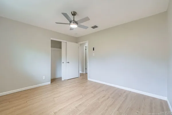 an empty room with wooden floor fan and windows