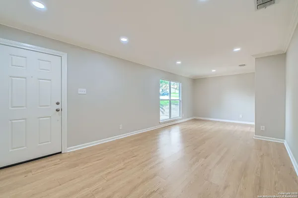 a view of an empty room with wooden floor and windows