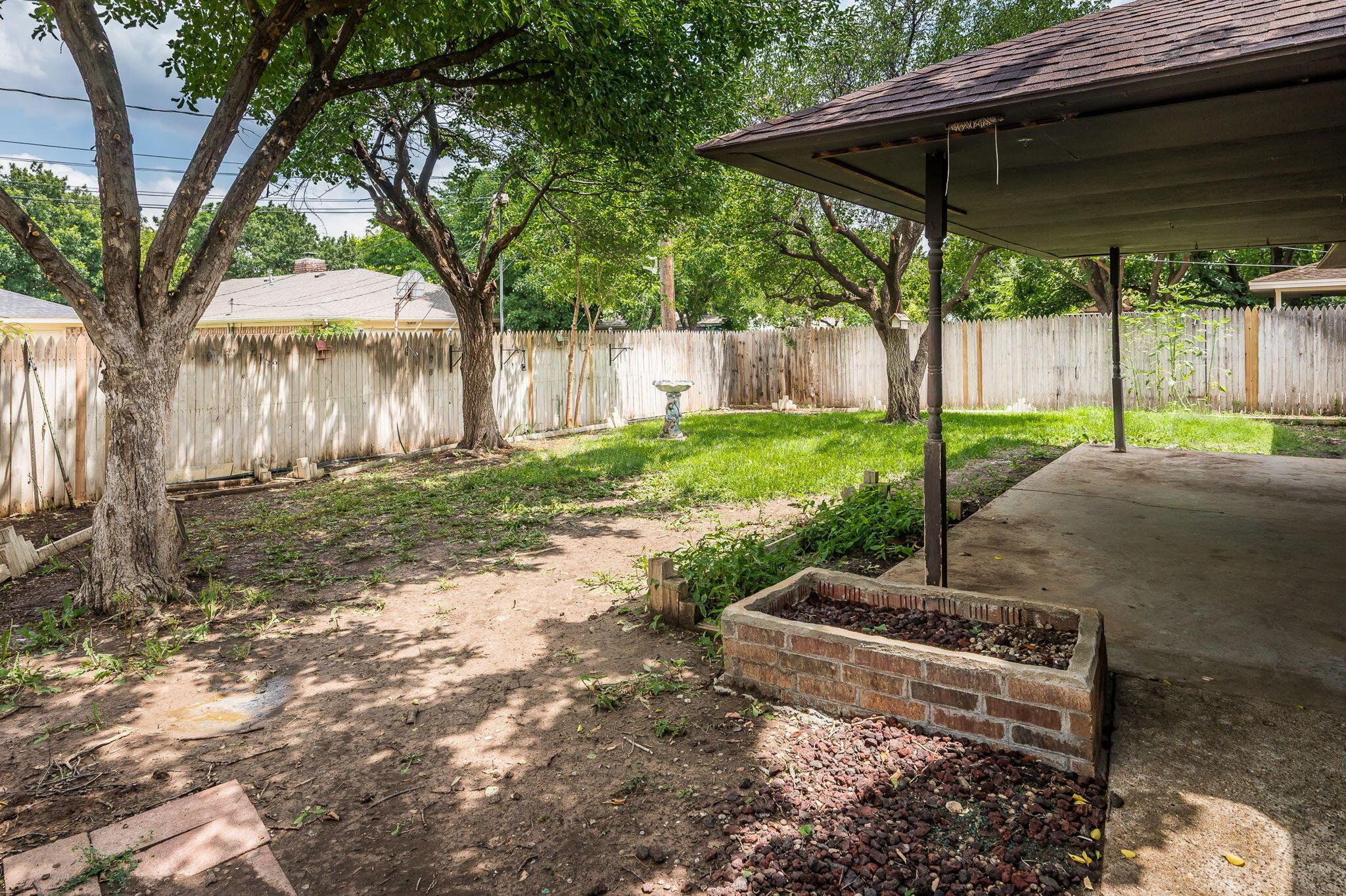 7830 Canode Drive Amarillo, TX 79121 - Photo 29 of 29 a view of a backyard with table and chairs under an umbrella