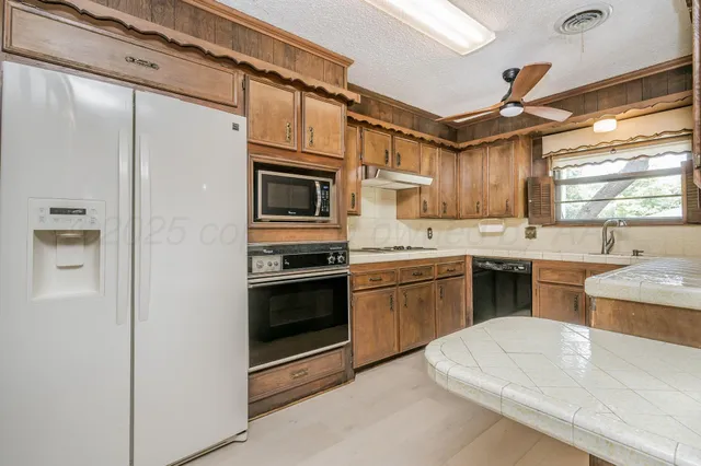 a kitchen with stainless steel appliances granite countertop a sink a stove a refrigerator with grey cabinets