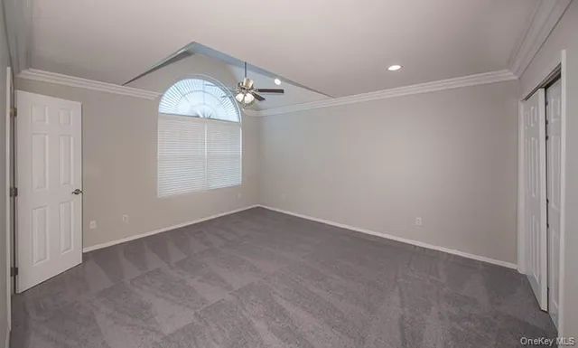 an empty room with a chandelier fan and windows