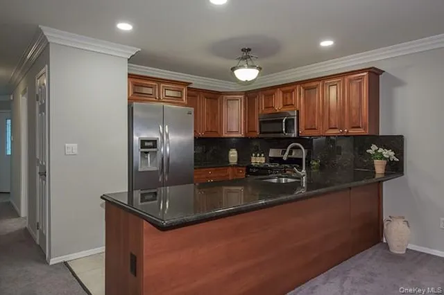 a kitchen with stainless steel appliances granite countertop a refrigerator a stove a sink a microwave and island