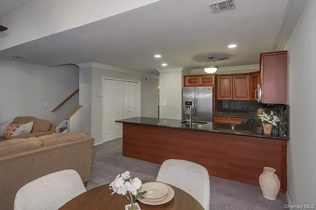 a kitchen with stainless steel appliances granite countertop a refrigerator a sink a stove with wooden cabinets and floor