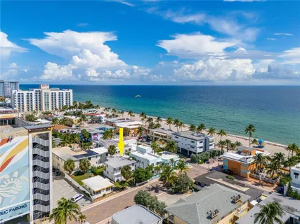 an aerial view of a city with lots of residential buildings ocean and mountain view in back