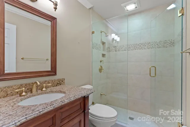 a bathroom with a granite countertop sink a toilet a mirror and shower