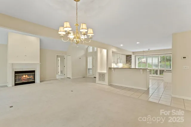 a view of a livingroom with a fireplace a chandelier and windows