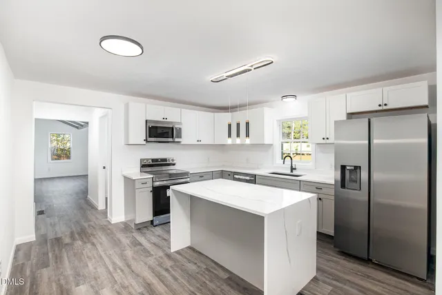 a kitchen with stainless steel appliances a refrigerator a stove a microwave oven a sink with island and chairs