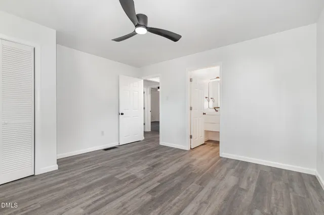 a view of empty room with wooden floor and ceiling fan