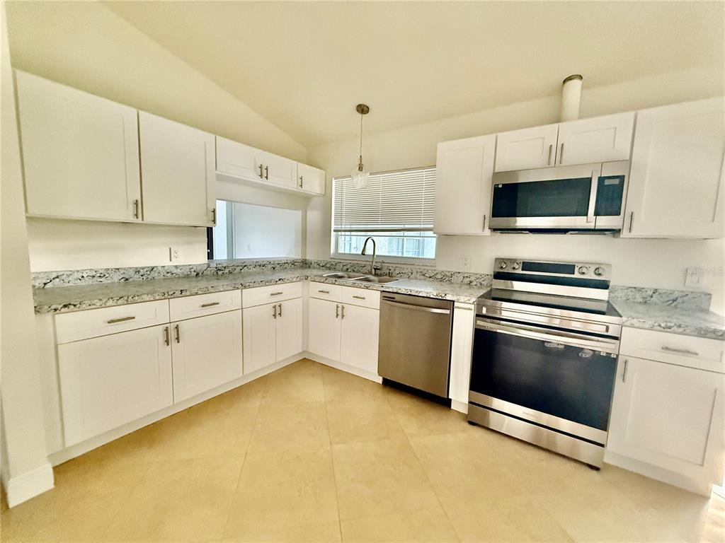970 Amy Ridge Court Kissimmee, FL 34747 - Photo 7 of 18 a kitchen with stainless steel appliances granite countertop a sink a stove a microwave and cabinets