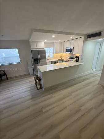 a room with stainless steel appliances wooden floor and chair