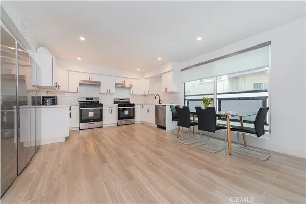 a view of kitchen with stainless steel appliances refrigerator stove microwave and chairs