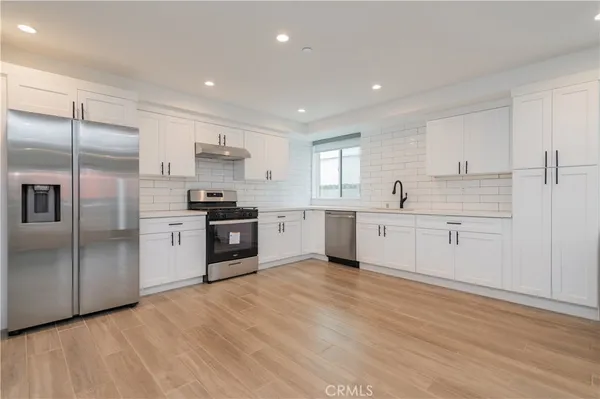 a large kitchen with a refrigerator sink and cabinets