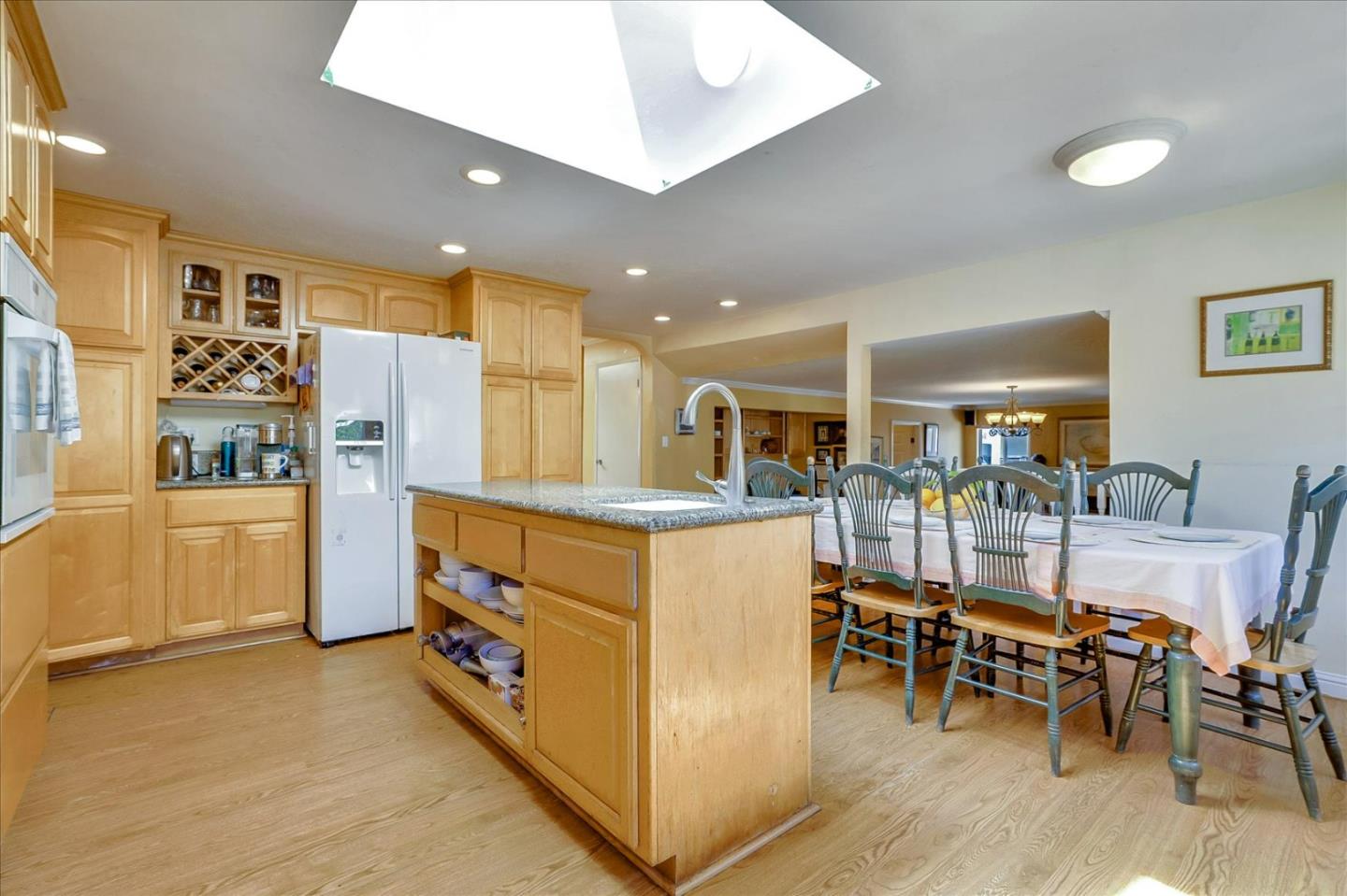 7166 Brooktree Way San Jose, CA 95120 - Photo 13 of 48 a kitchen with stainless steel appliances kitchen island granite countertop a refrigerator a stove a dining table and chairs with wooden floor