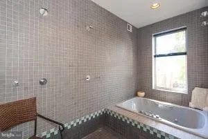 a bathroom with a tub a sink a window and shower