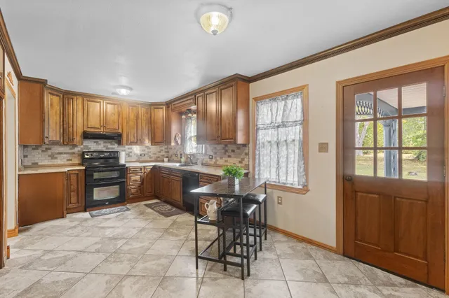 a kitchen with granite countertop wooden cabinets stainless steel appliances a window and a dining table