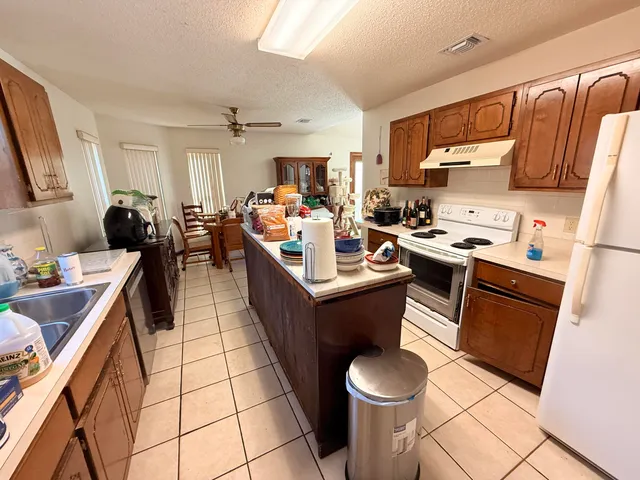 a view of kitchen with stainless steel appliances kitchen island granite countertop lots of counter top space