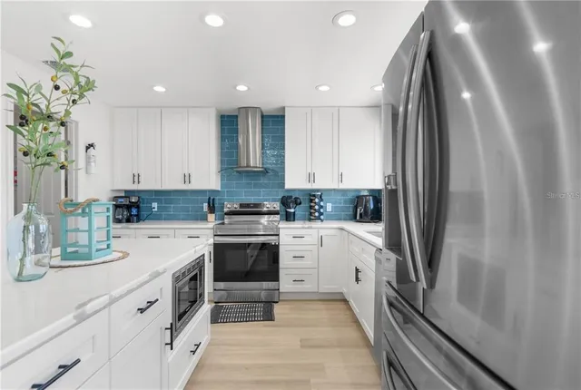 a kitchen with stainless steel appliances a refrigerator sink and white cabinets