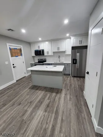 a living room with stainless steel appliances furniture a refrigerator a sink a microwave a refrigerator and cabinets
