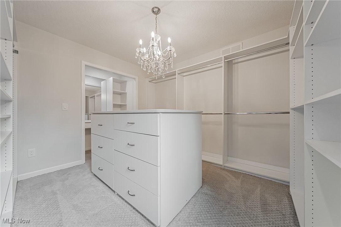 5270 Brainard Road Solon, OH 44139 - Photo 25 of 45 Spacious and beautiful custom primary suite closet featuring a chandelier, built in storage, island with storage and light colored carpet