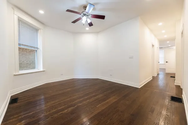 an empty room with wooden floor and a ceiling fan