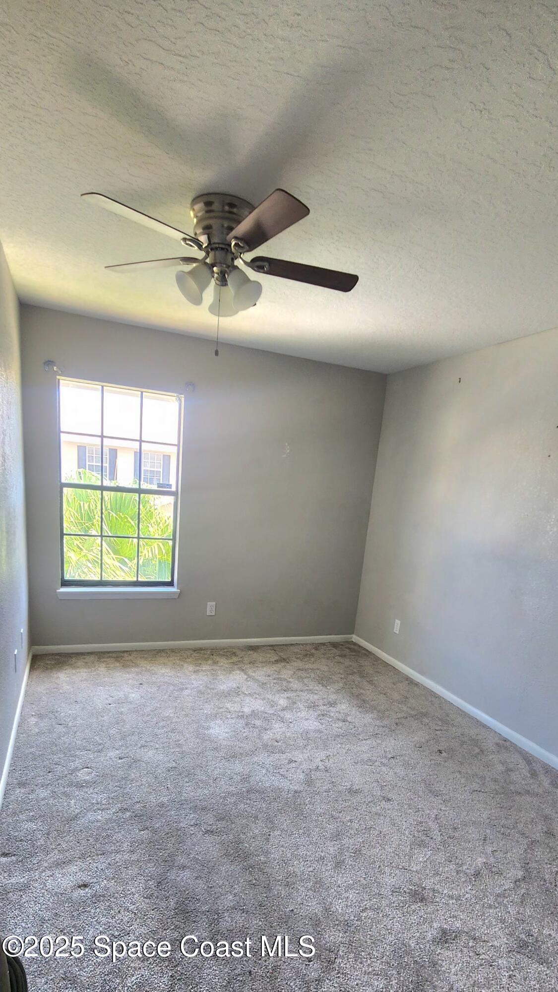 2014 Manor Drive Northeast Palm Bay, FL 32905 - Photo 22 of 24 en empty room with windows and chandelier fan