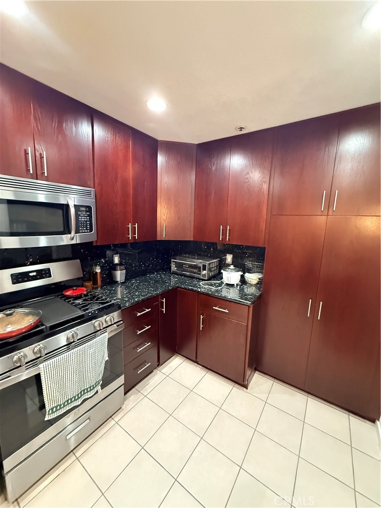 14630 Dickens Street, Unit 307 Sherman Oaks, CA 91403 - Photo 15 of 41 a kitchen with stainless steel appliances granite countertop a stove a sink and a microwave