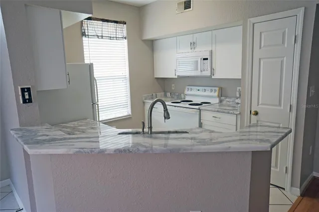 a kitchen with kitchen island white cabinets and window