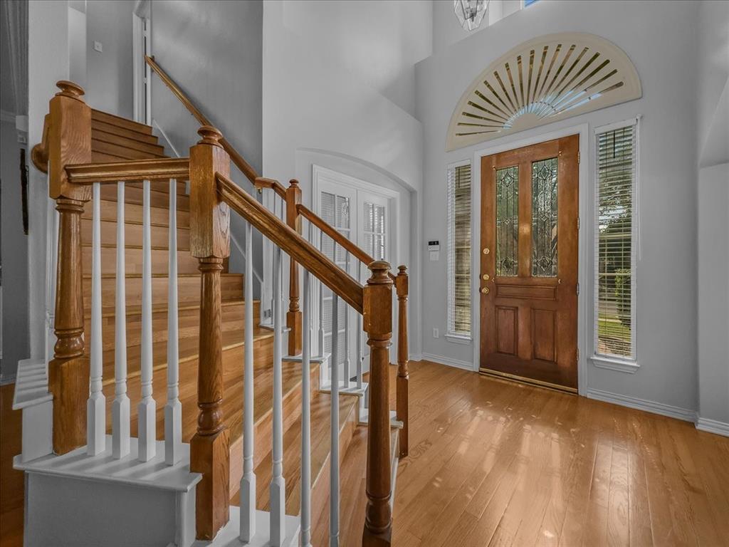 6206 Hidden Springs Lane Garland, TX 75044 - Photo 12 of 24 Foyer entrance with wood-type flooring, baseboards, stairway, and a towering ceiling