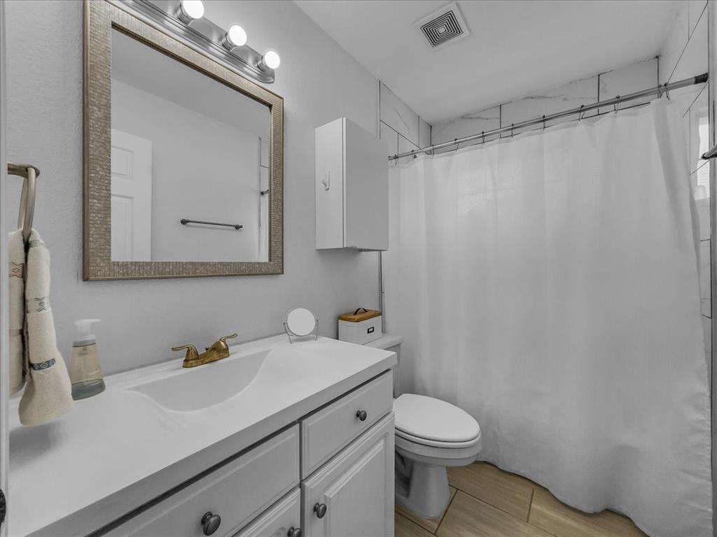 6206 Hidden Springs Lane Garland, TX 75044 - Photo 20 of 24 Full bath featuring vanity, toilet, wood finished floors, and a shower with shower curtain