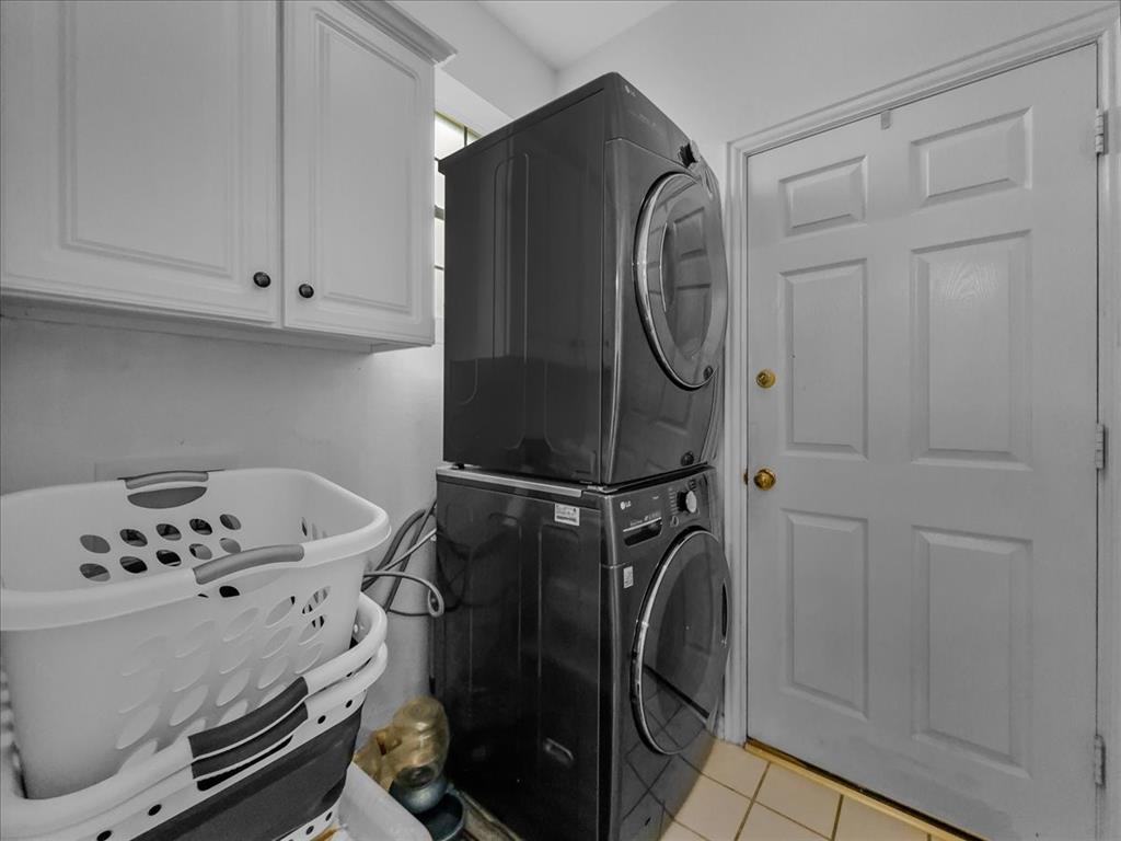 6206 Hidden Springs Lane Garland, TX 75044 - Photo 22 of 24 Laundry room featuring stacked washing machine and dryer, light tile patterned flooring, and cabinet space