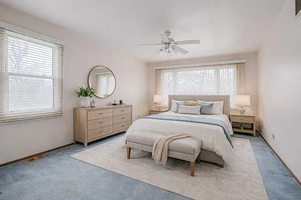a bedroom with a bed a chandelier and dresser